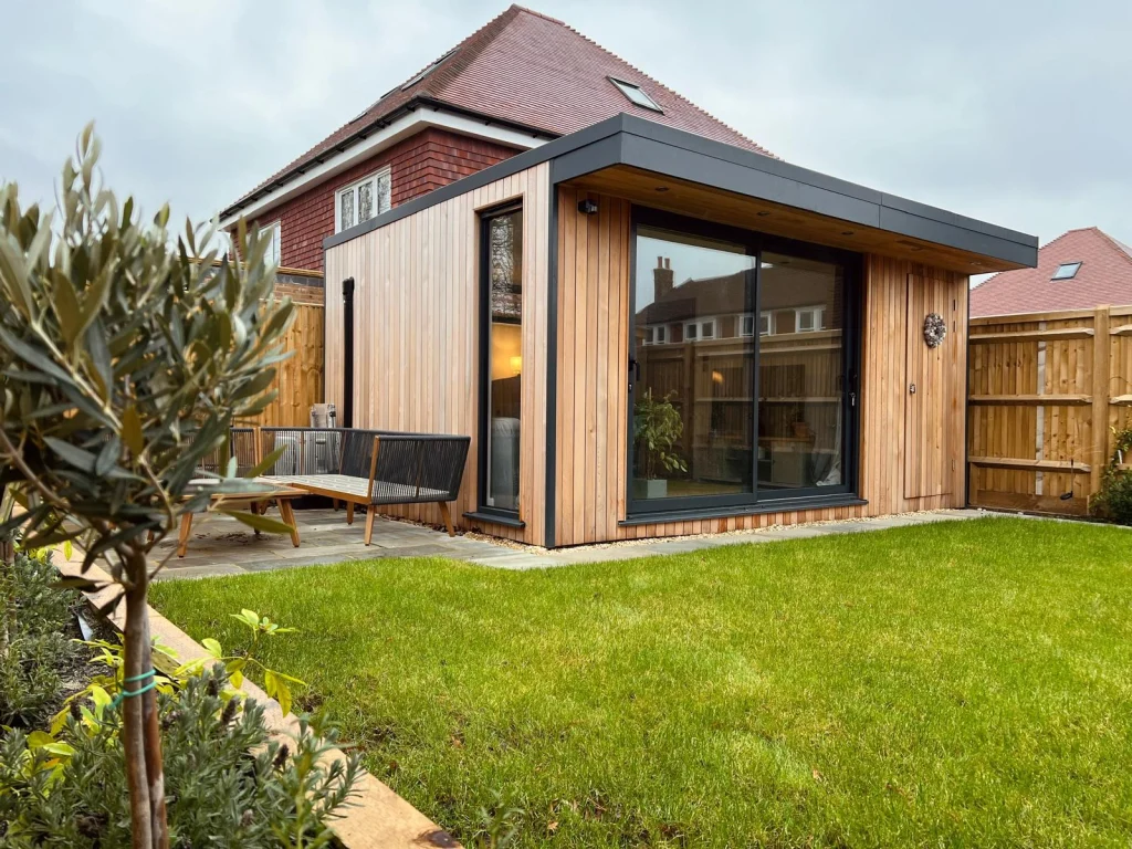 Pitched-roof garden room on a lawn with a paved path